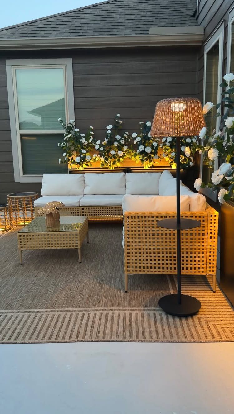 Wicker outdoor sectional sofa with white cushions and a matching coffee table on a patio.