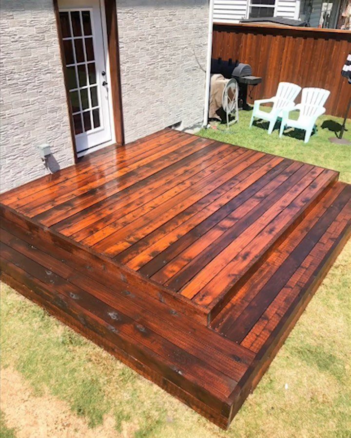 A dark reddish-brown stained cedar wood deck attached to a white brick house.