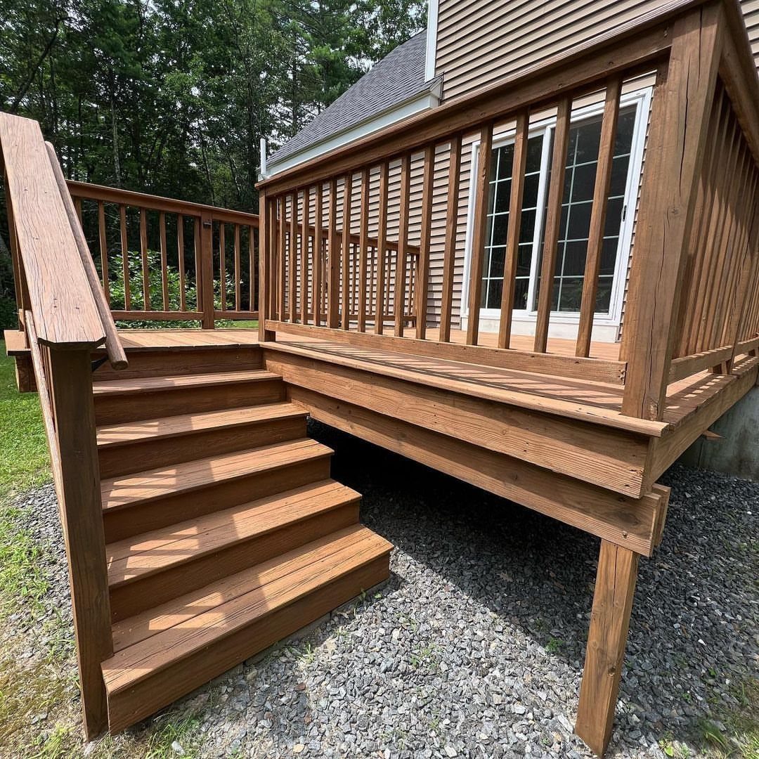 A wooden outdoor deck with stairs finished in a warm brown semi-transparent stain.