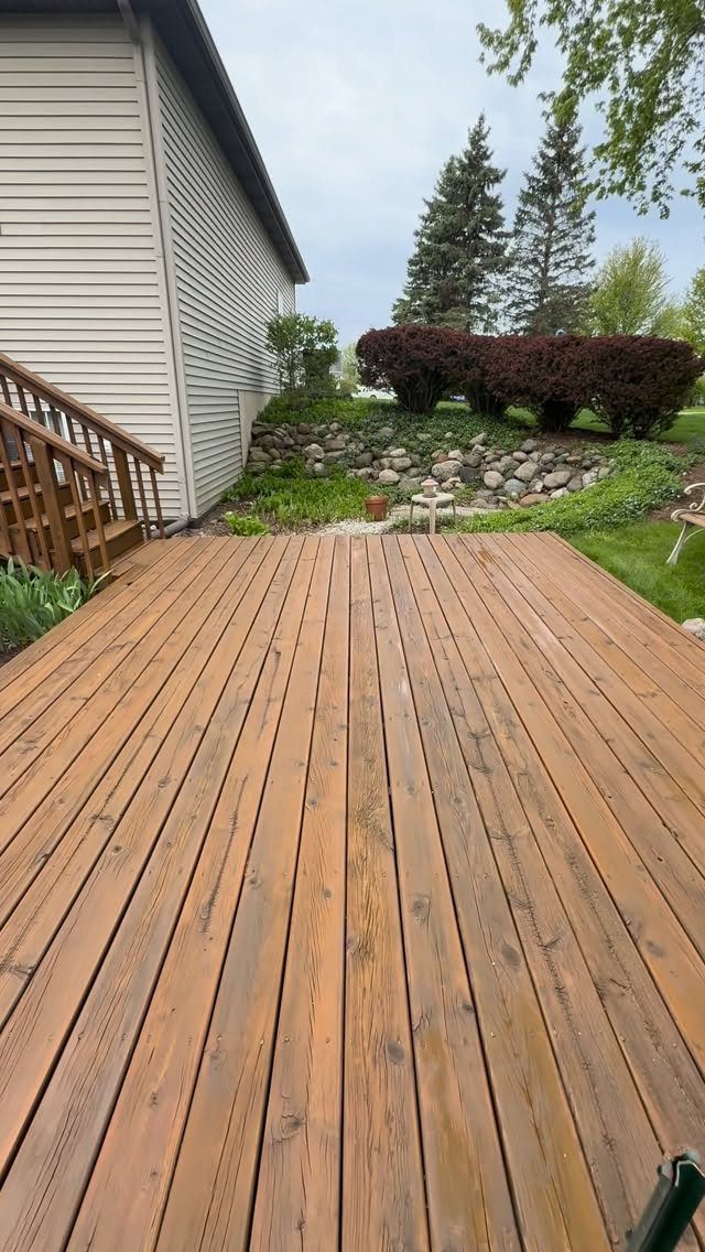 A wooden deck with a warm cedar stain overlooking a landscaped backyard garden.