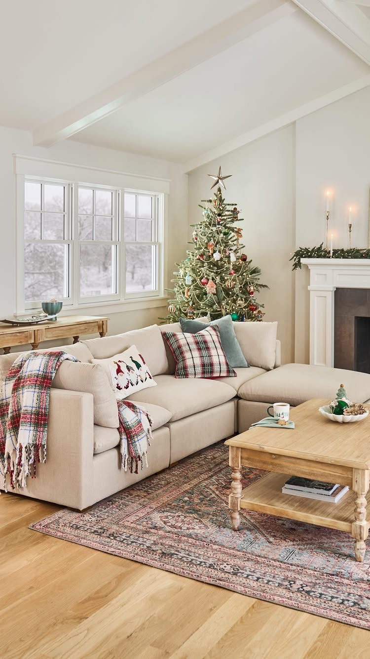 Cream sectional sofa with red and green plaid pillows and a patterned throw blanket in a living room.