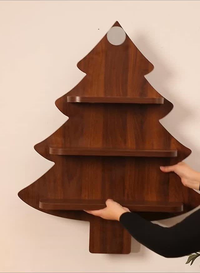Christmas Tree Shelf: 6 Ideas from 2x4 Builds to Live Edge 6 Hands holding a dark wooden Christmas tree shaped wall shelf against a light wall.