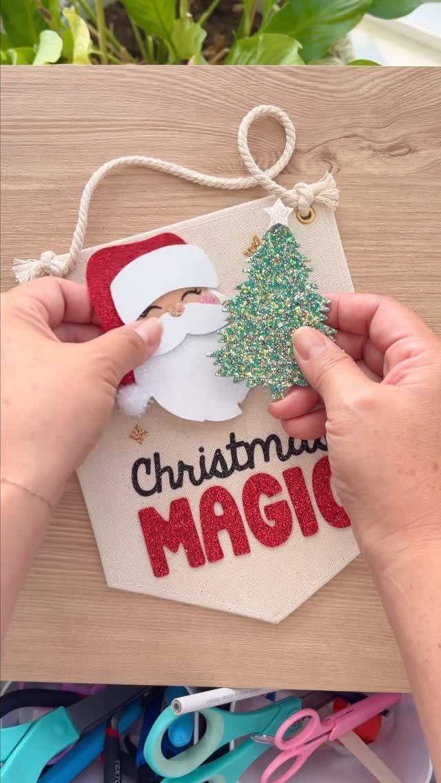 Hands placing a glittery green tree onto a Christmas magic fabric banner.