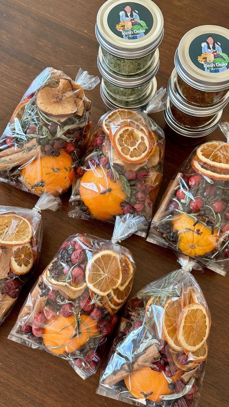 Clear bags filled with dried citrus, cranberries, and cinnamon sticks on a wooden table.