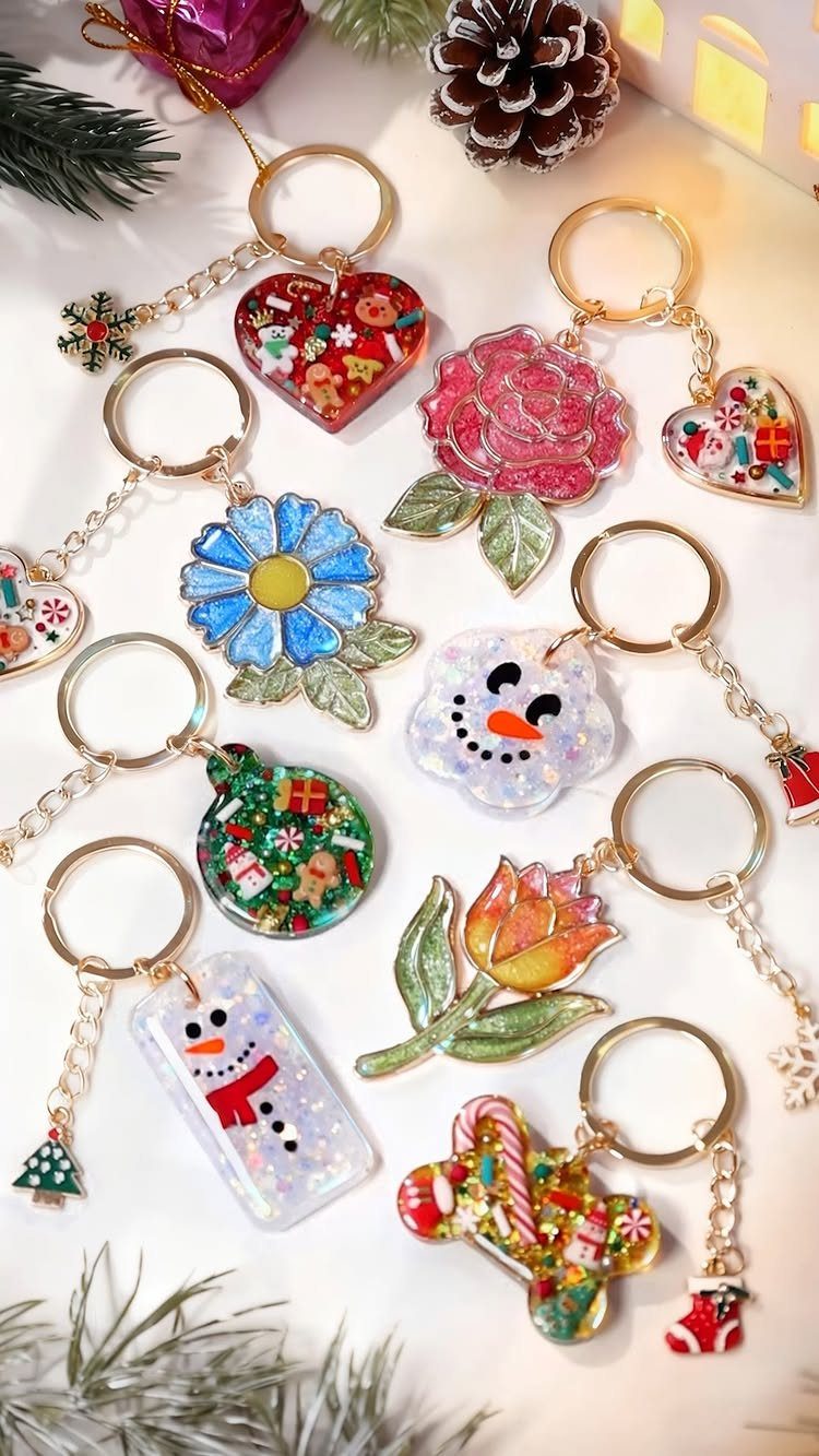 Colorful resin keychains in various shapes scattered among pine needles and pinecones.