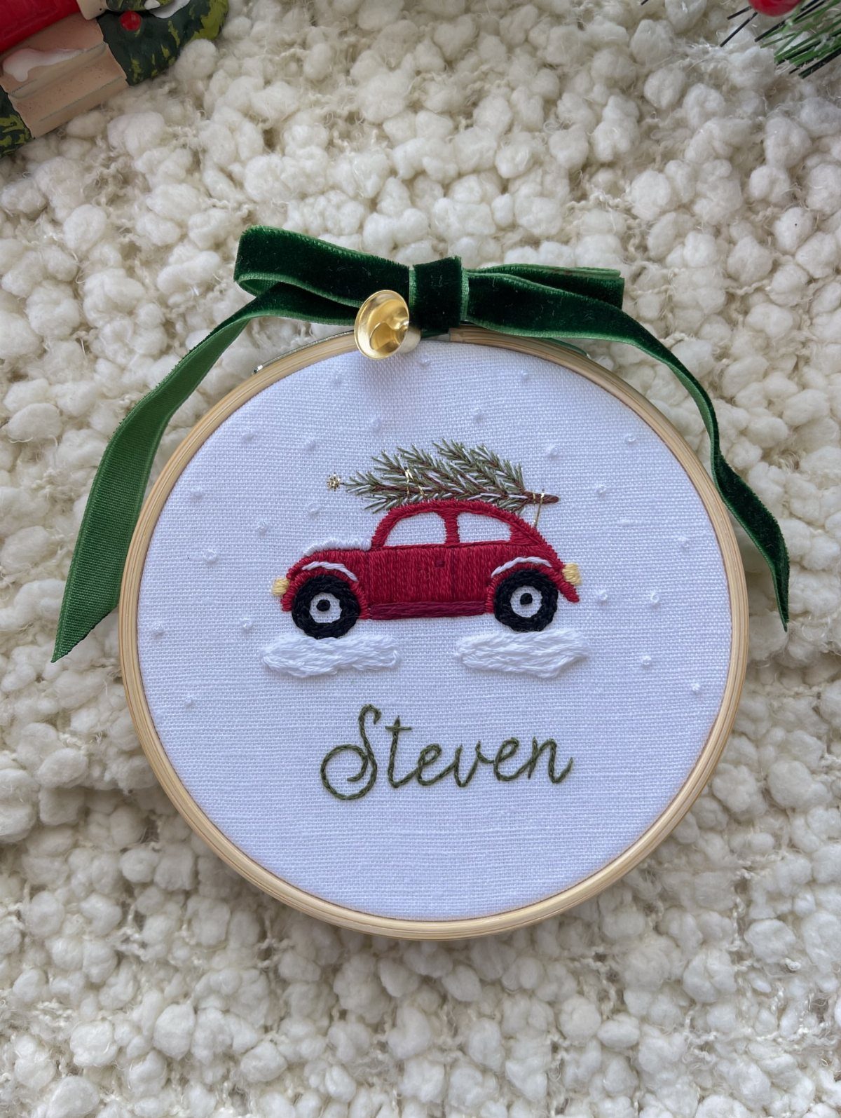 Embroidered ornament featuring a red car with a Christmas tree and the name Steven.