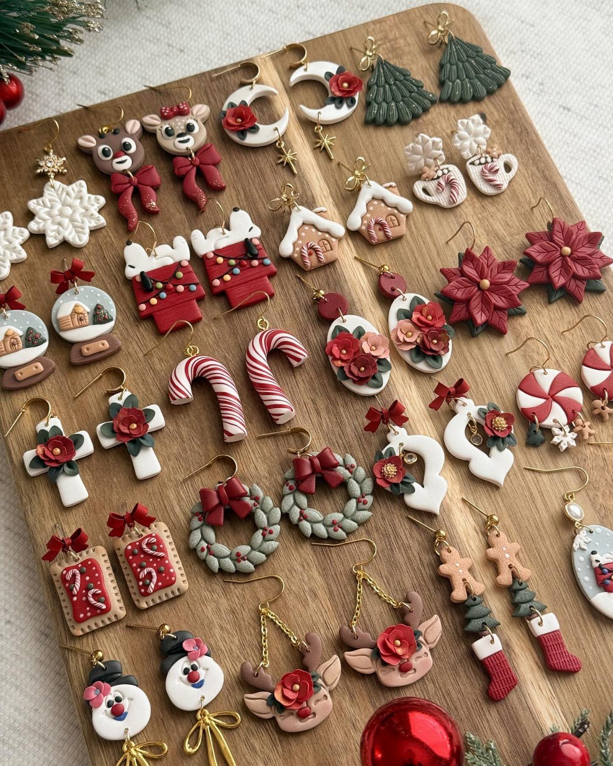 Handmade Christmas-themed clay earrings arranged on a wooden board, featuring snowmen, reindeer, and festive patterns.