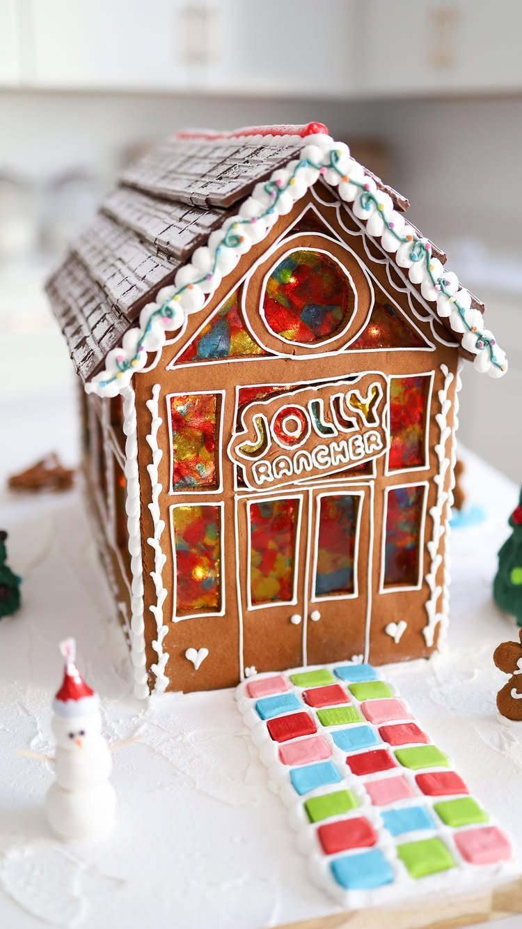 A decorated gingerbread house filled with colorful Jolly Rancher candies and a candy path.