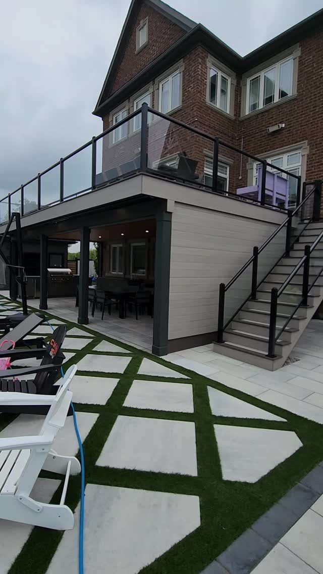 Deck with Patio Underneath: 5 Layouts That Actually Work 5 A multi-level outdoor living space featuring a raised deck with glass railings over a covered patio.