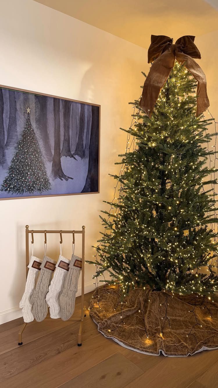 Decorating for Christmas: 12 Ideas That Work in Real Rooms 5 A lit Christmas tree with a large brown bow stands next to a stocking holder.