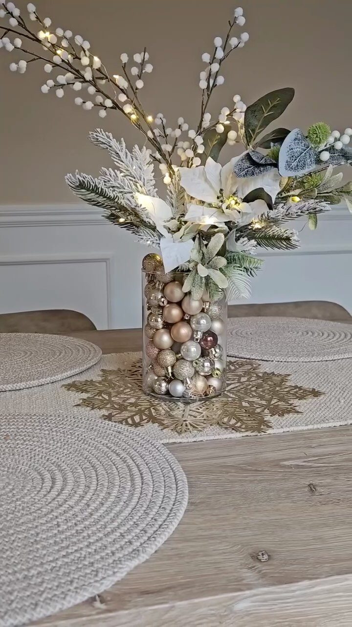 Decorating for Christmas: 12 Ideas That Work in Real Rooms 4 Glass vase filled with gold ornaments and white poinsettias on a wooden dining table.