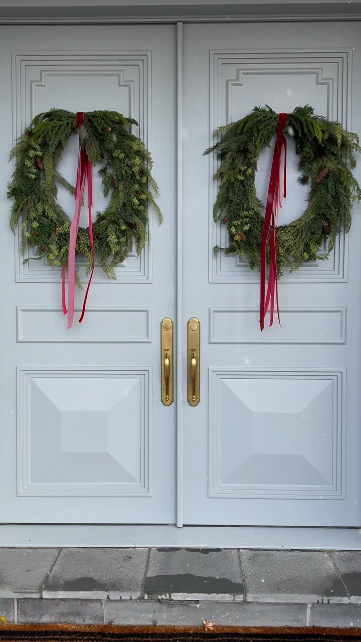 Decorating for Christmas: 12 Ideas That Work in Real Rooms 3 Two green evergreen wreaths with long red ribbons hanging on light grey double doors.