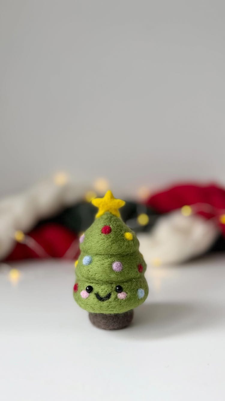 A small green felt Christmas tree with a smiling face and a yellow star topper.
