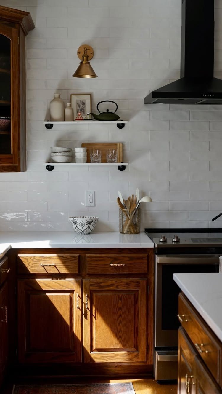 Wooden kitchen cabinets with natural finish under white countertops and subway tile backsplash.