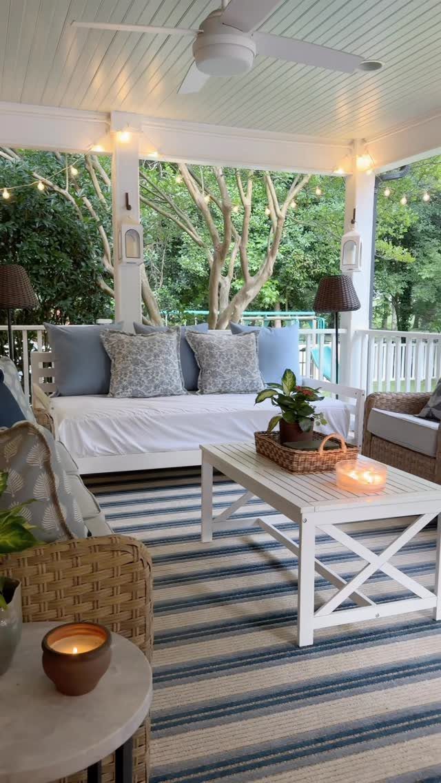 DIY Patio Couch: 8 Projects to Build for Any Budget 4 White wooden outdoor daybed with blue and patterned grey cushions on a covered patio.