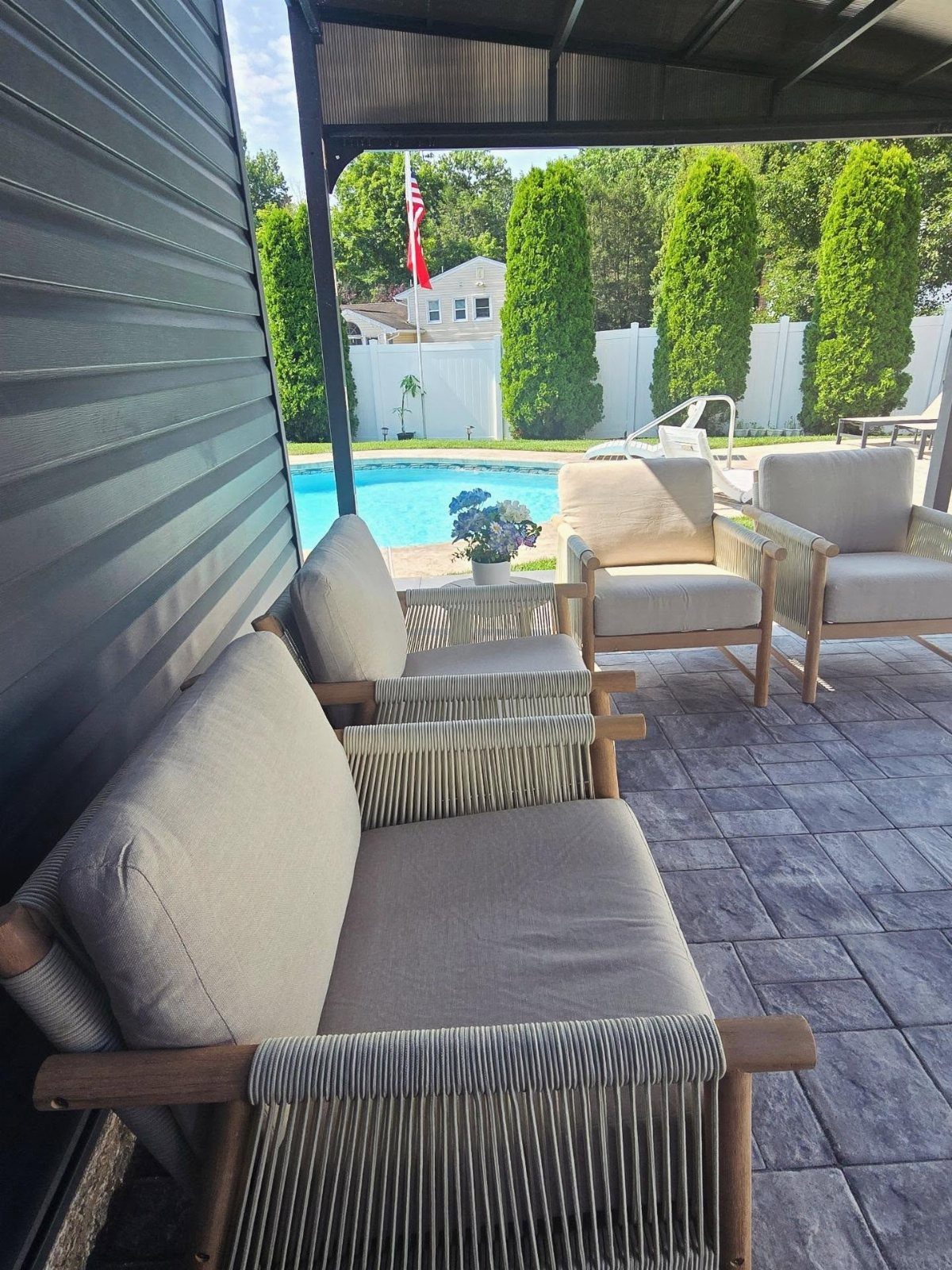 DIY Patio Couch: 8 Projects to Build for Any Budget 6 Wooden patio couch with beige cushions and rope weaving overlooking a swimming pool and garden.