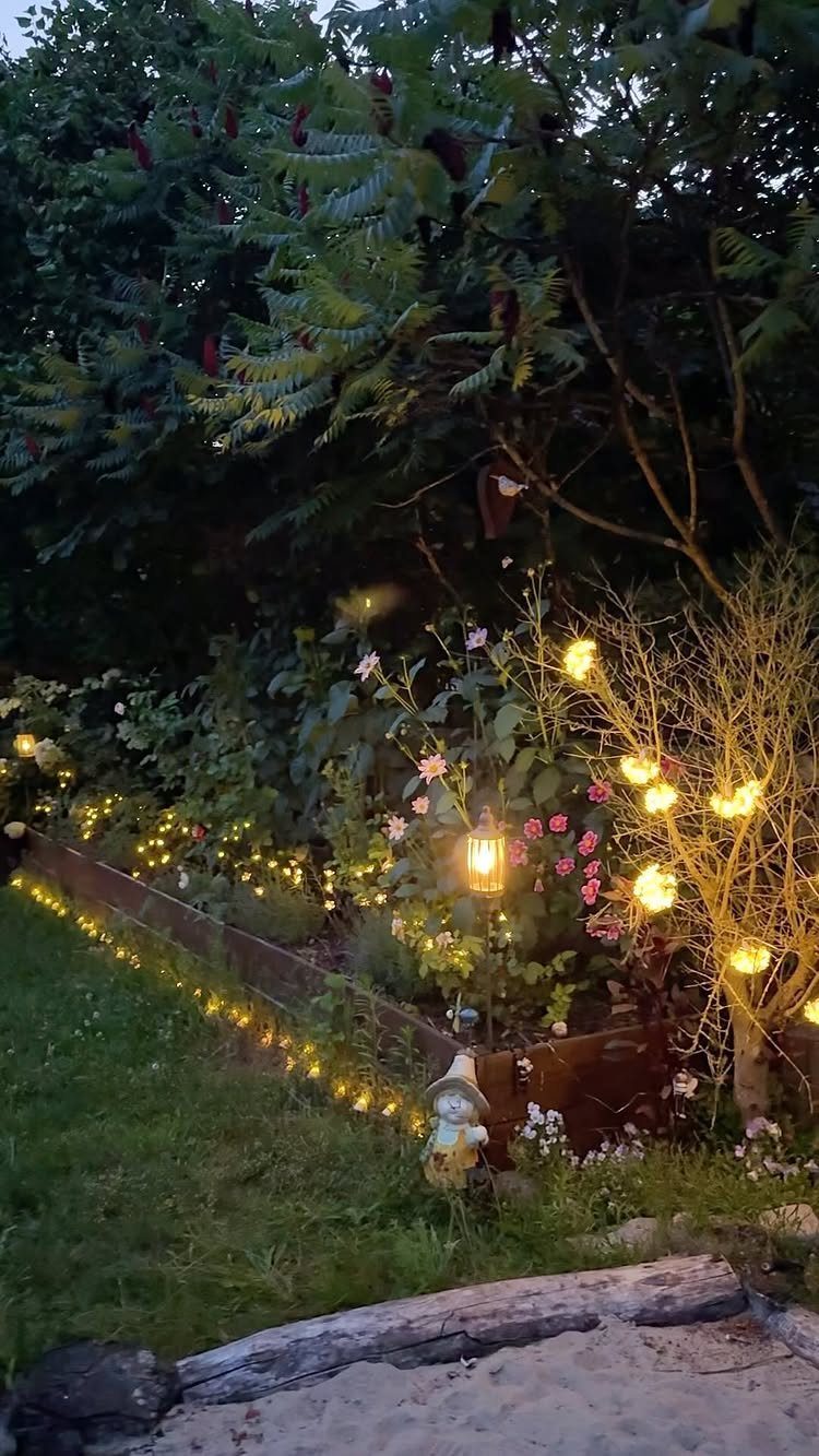 Easy Garden DIY: 18 Projects for a Yard That Feels Finished 5 Glowing string lights decorating a lush garden bed filled with plants and flowers at dusk.
