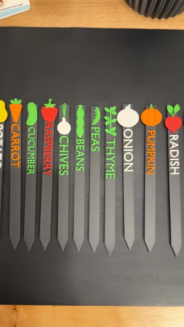 Easy Garden DIY: 18 Projects for a Yard That Feels Finished 6 Colorful garden plant labels with vegetable names and icons laid out on a dark background.