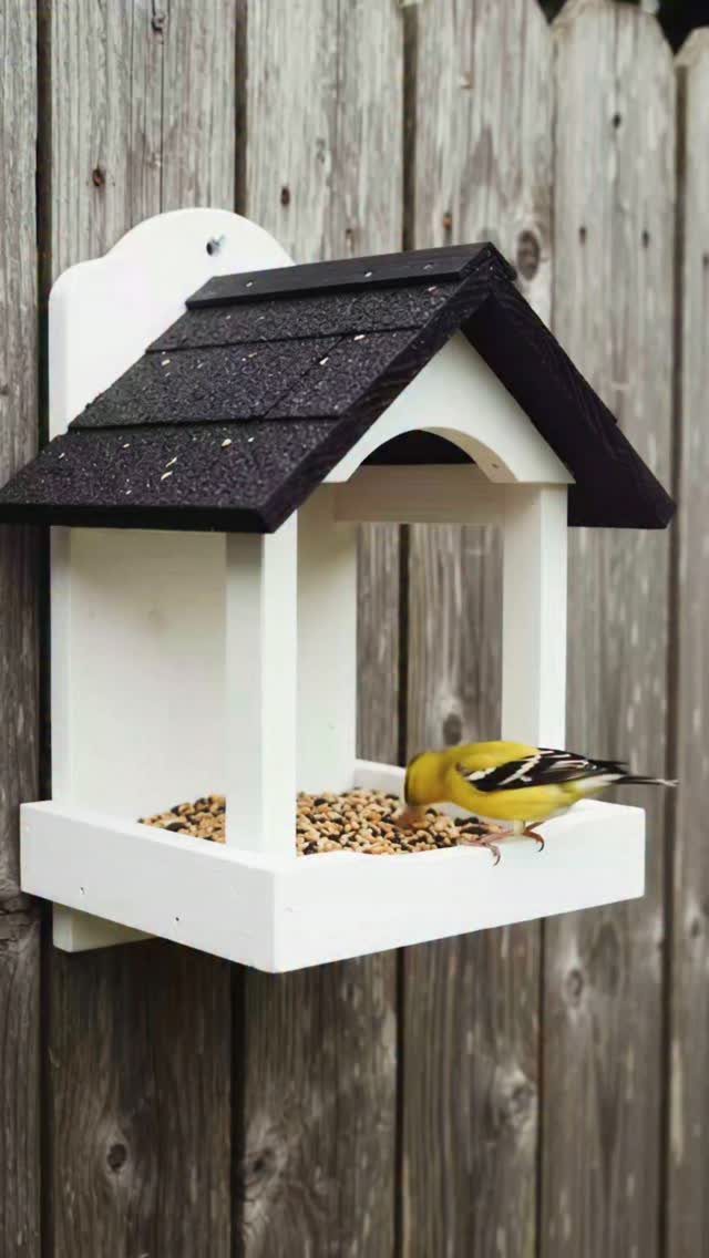 Easy Garden DIY: 18 Projects for a Yard That Feels Finished 16 A yellow bird eats seeds from a white wooden bird feeder mounted on a fence.