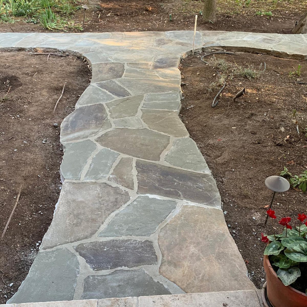 Easy Garden DIY: 18 Projects for a Yard That Feels Finished 10 Irregular flagstone pathway winding through a garden bed of dark soil and mulch.