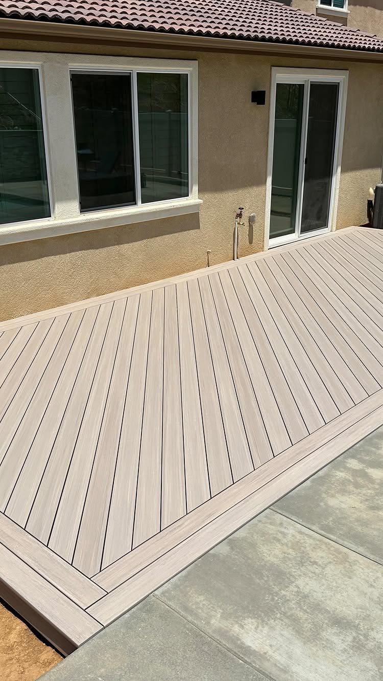 10 Front Yard Decks Ground Level That Welcome Guests First 10 Light grey composite deck with diagonal planks installed at ground level next to a house.