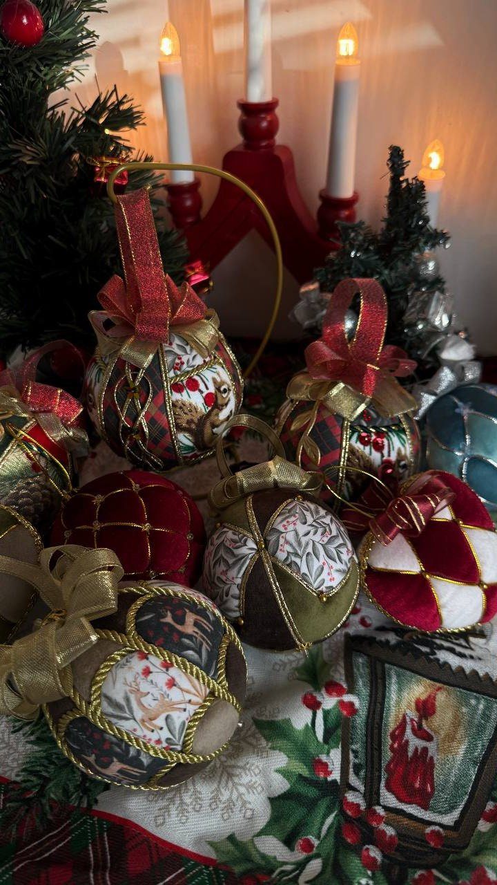 Fabric covered Christmas ornaments with gold trim and bows arranged on a festive holiday table.