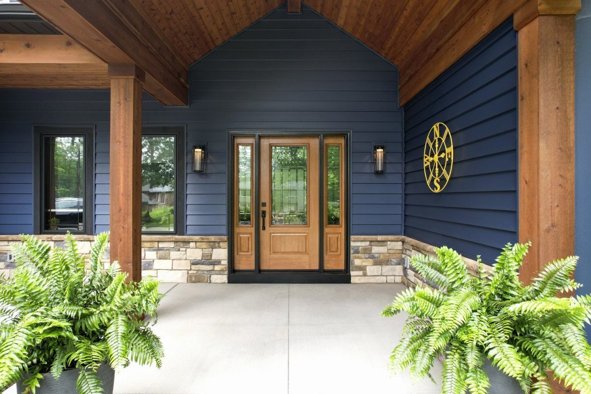 Navy blue siding on a modern house with a natural wood door and stone accents.
