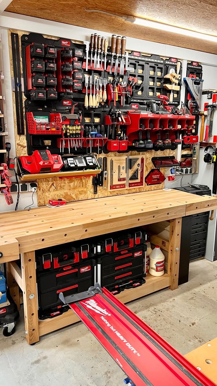 9 Multi Use Garage Ideas for Living, Work, and Play 3 A wooden workbench sits below a pegboard wall organized with various red and black tools.