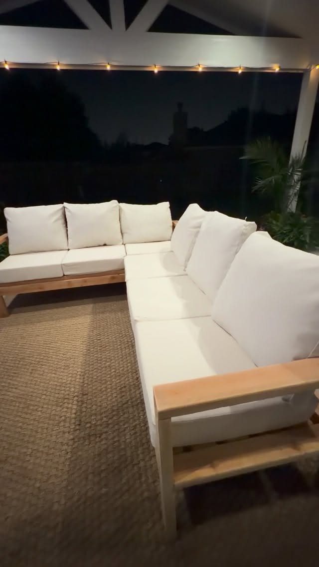 L-shaped outdoor sectional sofa with white cushions and light wood frame on a patio.