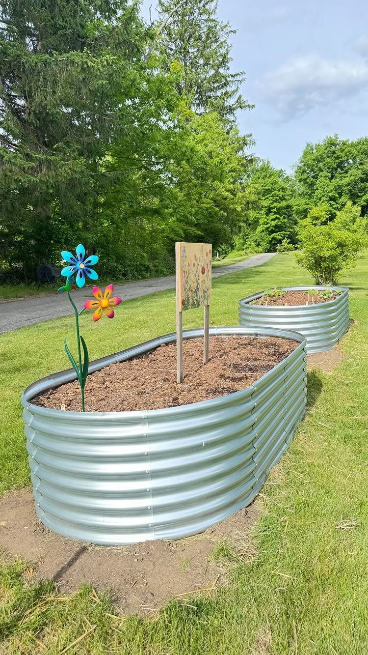 7 Vegetable Garden Box Ideas for Every Backyard Space 6 Two corrugated metal raised garden beds sit on a green lawn near a wooded area.